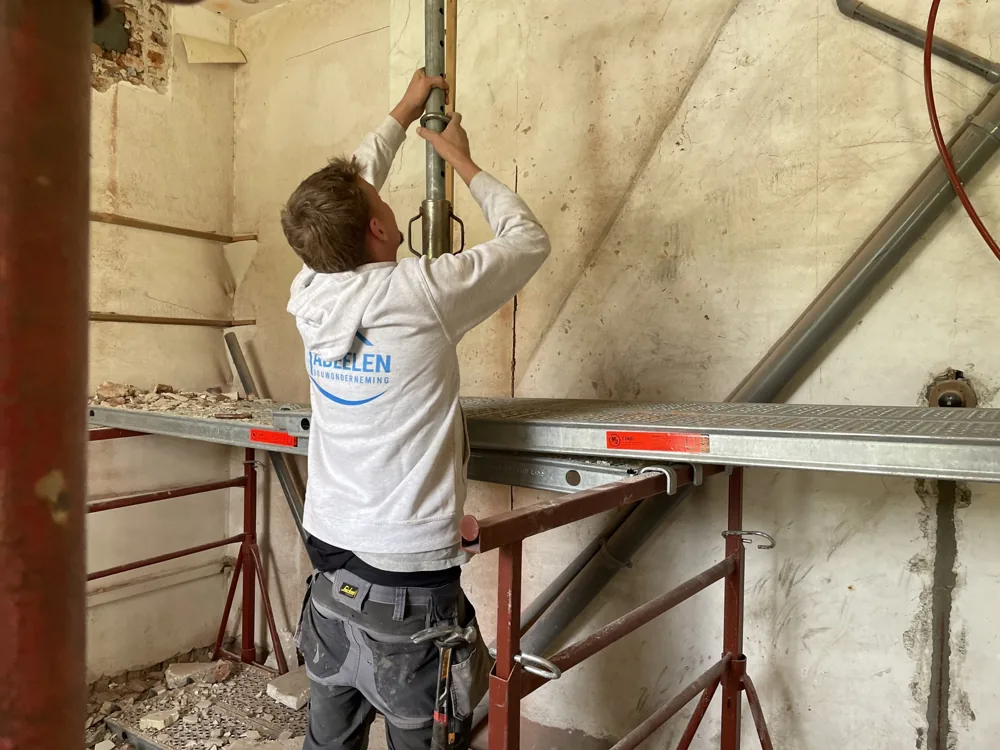 Vakman aan het werk op een steiger tijdens een renovatie